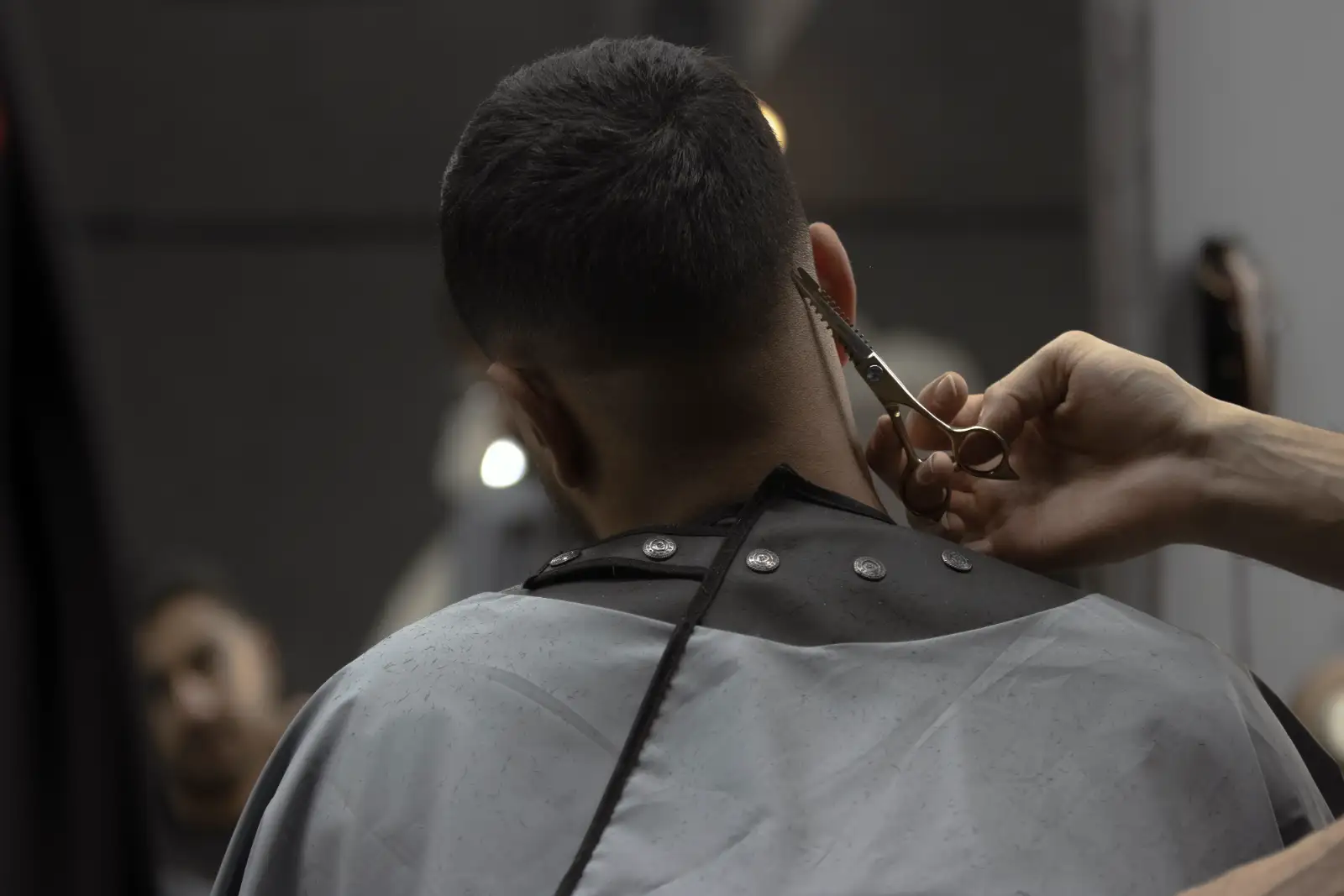 A barber cutting a customer’s hair with scissors